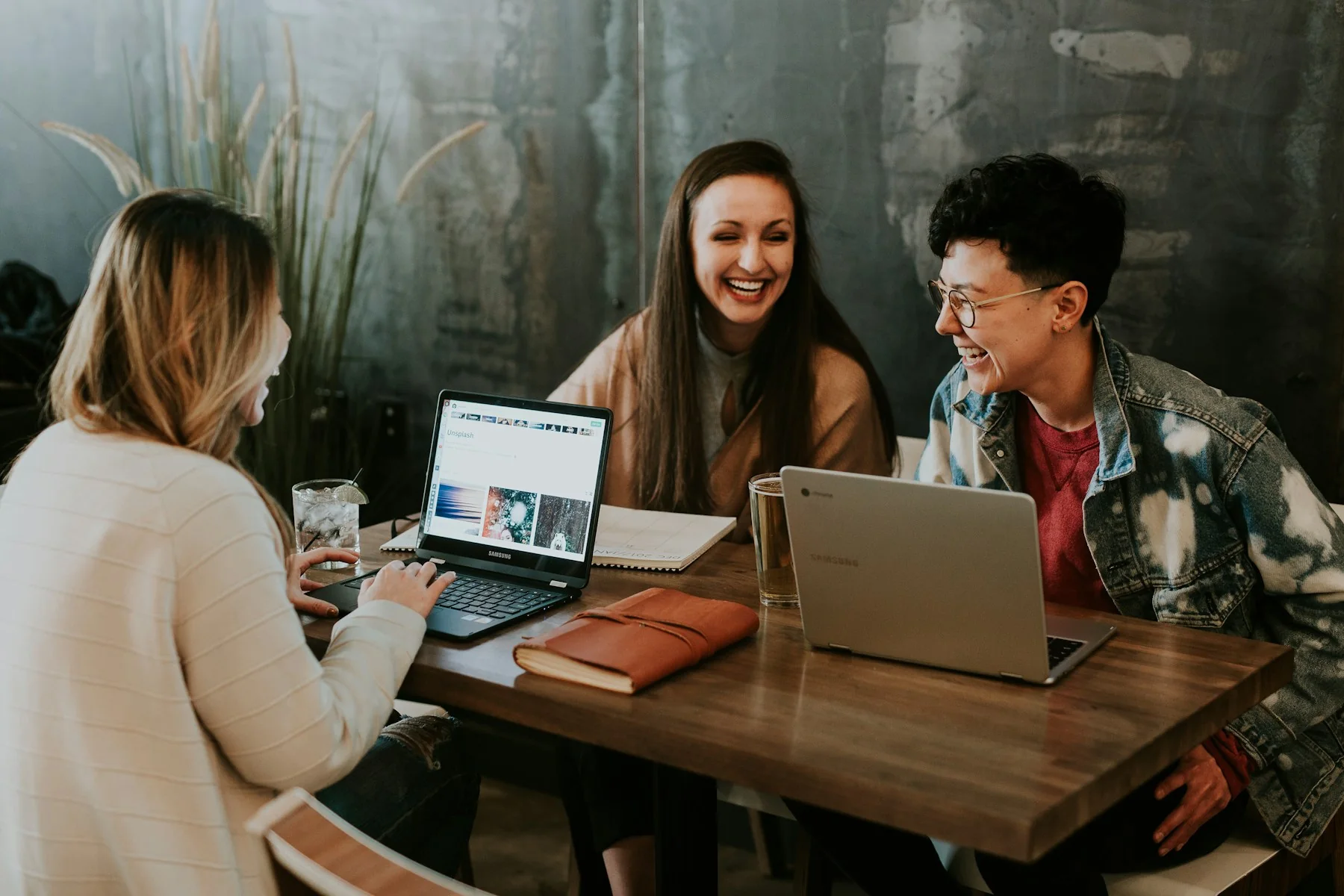 A small creative team reviewing content together around a laptop